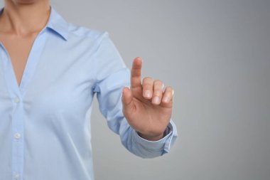 Gri arkaplana dokunan kadın, eline odaklan.