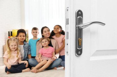 Öğretmen ve çocuklarla modern sınıfa açılan ahşap kapı.