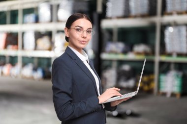 Toptan ve lojistik konsepti. Depo 'da dizüstü bilgisayar kullanan yönetici