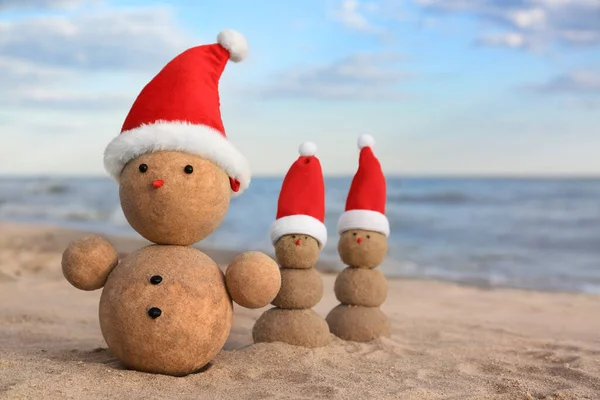 Bałwanów Piasku Czapkami Mikołaja Plaży Pobliżu Morza Święta Bożego Narodzenia — Zdjęcie stockowe