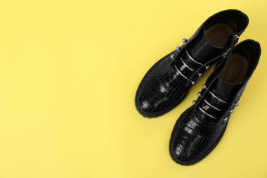 Sarı arka planda bir çift şık ayak bileği çizmesi, üst manzara. Metin için boşluk