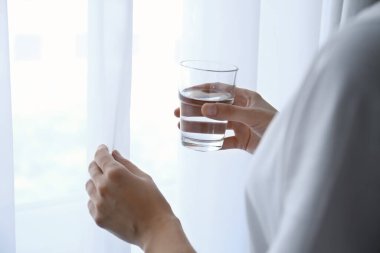 Kadın elinde cam bardak, pencerenin yanında, yakın plan.