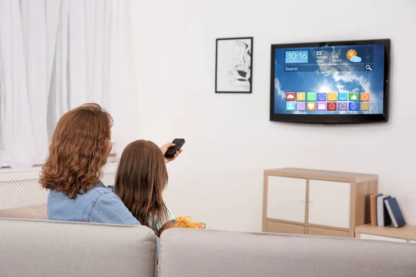 Mother and daughter watching smart TV in living room