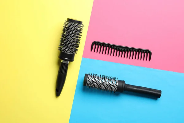 Hair brushes and comb on color background, flat lay