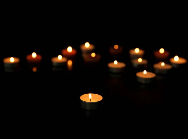 Many burning tealight candles on dark background