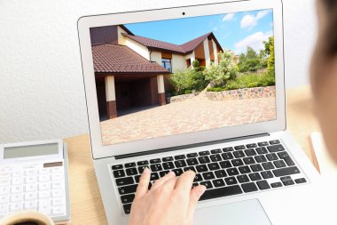 İş kadını ya da emlakçı bilgisayarı kullanarak online emlak portföyünü inceliyor.