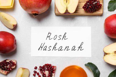 Beyaz masa üzerinde ROSH HASHANAH, elma, bal ve nar içeren kart, düz yatıyordu