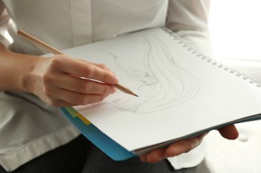 Not defterine kurşun kalemle kızın portresini çizen kadın, yakın plan.