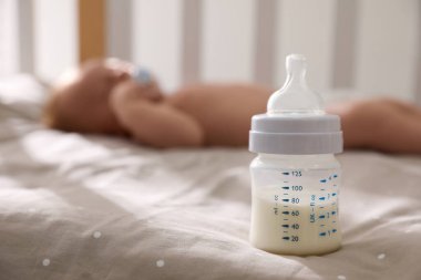 Karyolada uyuyan sağlıklı bebek, sütle şişeye odaklan.