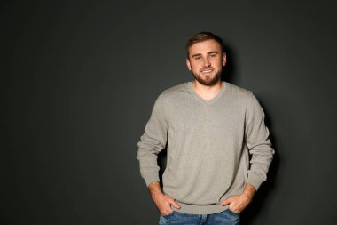 Siyah arka planda kalın kazak giyen yakışıklı bir adam. Metin için boşluk