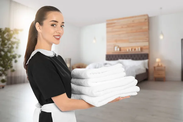 ホテルの部屋できれいな折り畳まれたタオルを持つ美しい客室メイド — ストック写真