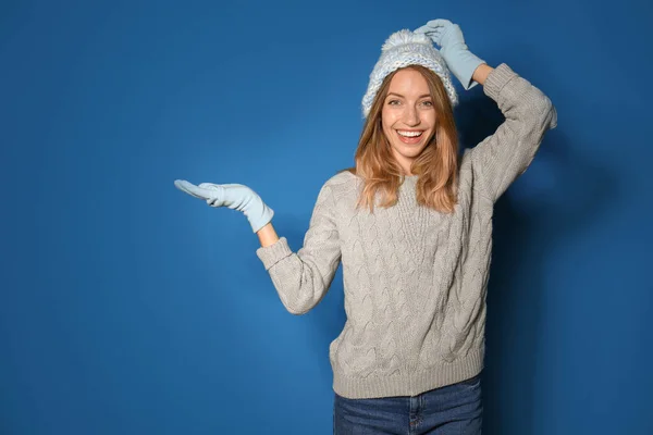 快乐的年轻女子 身穿暖和的毛衣 头戴针织的帽子 头戴蓝色背景的手套 — 图库照片