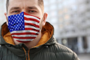 Açık havada Amerikan bayrağı desenli maske takan bir adam, yakın plan. Tehlikeli bir virüs.