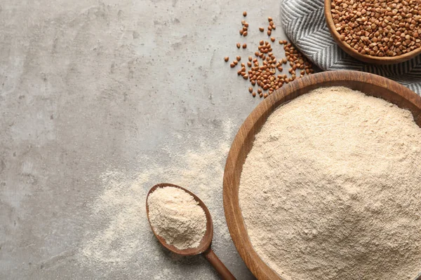 Flat lay composition with buckwheat flour on grey table, space for text