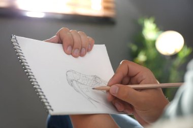 Kapalı alanda kurşun kalemle yılan çizen adam.