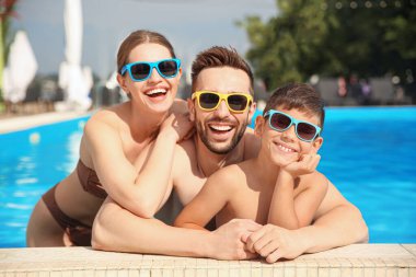 Güneşli bir günde havuzda mutlu bir aile.