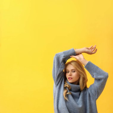 Sarı arka planda sıcak mavi süveter giyen güzel genç bir kadın. Metin için boşluk