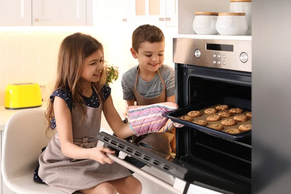 可爱的小孩在厨房里从烤箱里拿出饼干 烹调糕点 — 图库照片