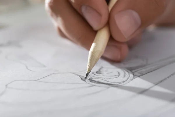 Man drawing portrait with pencil in notepad, closeup