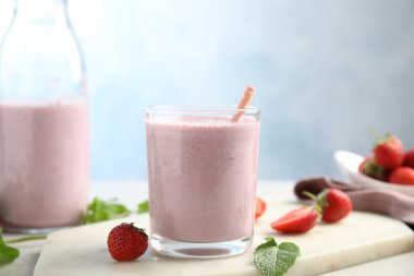 Çilekli lezzetli milkshake ve beyaz mermer tahtada nane şekeri.