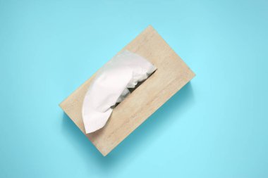 Açık mavi arka planda kağıt mendilli ahşap tutucu, üst görünüm