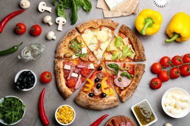 Düz kompozisyon, gri masanın üzerinde farklı lezzetli pizzaların dilimleri vardı.