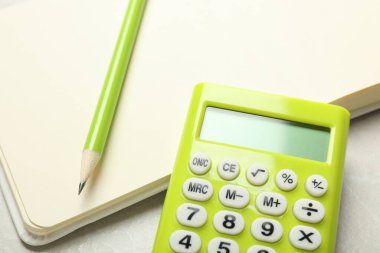 Hesap makinesi, defter ve kalem ışık masasında, yakın plan. Vergi muhasebesi