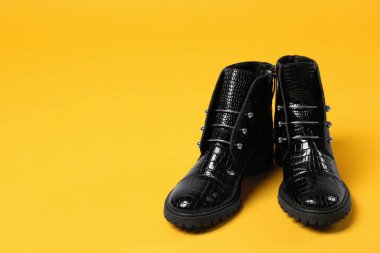 Sarı arka planda bir çift şık ayak bileği çizmesi. Metin için boşluk