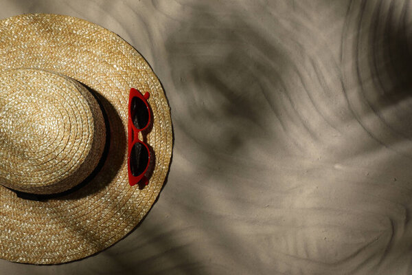 Straw hat and sunglasses on sand, top view. Beach accessories