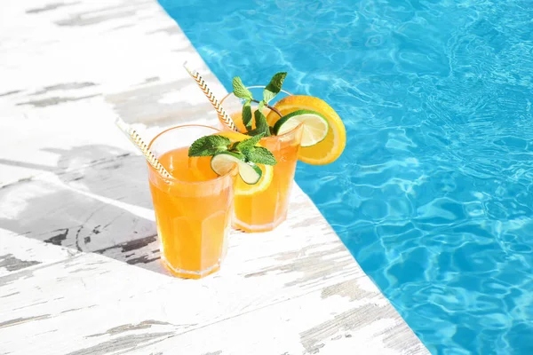 Güneşli bir günde, açık havuzun yanındaki bardaklarda taze bir kokteyl.