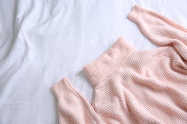 Pembe, sıcak süveter, beyaz buruşuk kumaş, üst manzara. Metin için boşluk