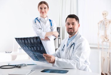Orthopedists examining X-ray picture at desk in clinic clipart