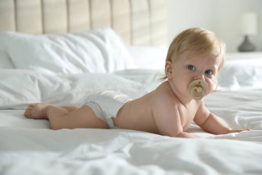 Bebek bezi takmış, evde emzik takmış tatlı bir bebek.