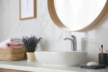 Banyo tezgahında lavabo, çiçekler ve havlular var. Tasarım için fikir