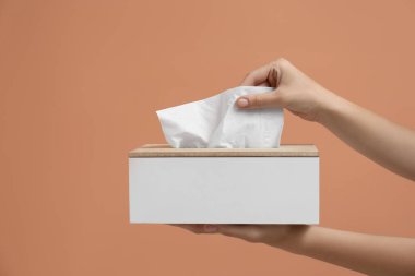 Açık kahverengi arka plandan kağıt mendil alan kadın, yakın plan.