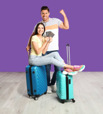 Bavulları ve pasaportları olan mutlu bir çift. Yaz tatili için mor duvarın yanında. Tatil gezisi