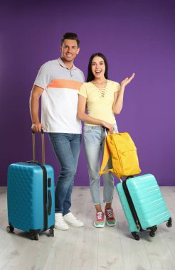 Mor duvarın yanında yaz tatili için bavulları olan mutlu bir çift. Tatil gezisi