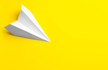 Sarı arka planda beyaz kağıt uçak, üst manzara. Metin için boşluk