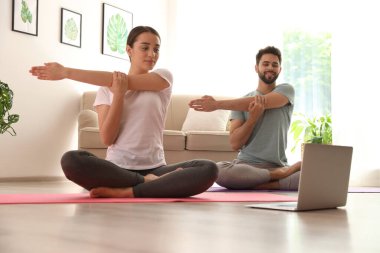 Çift evde koronavirüs salgını sırasında online ders izlerken yoga yapıyor. Sosyal uzaklık
