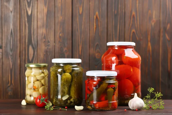 Jars of pickled vegetables on wooden table