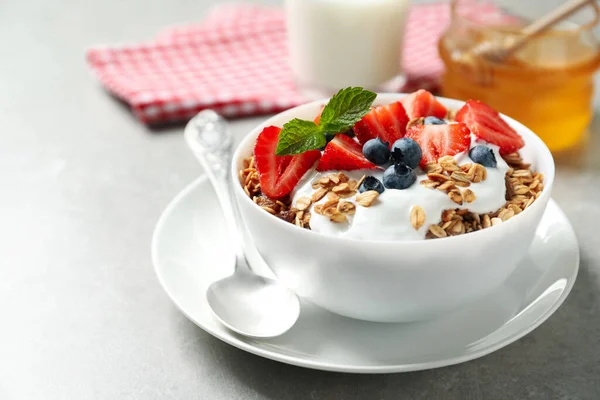 带有酸奶和浆果的味道鲜美的格拉诺拉早餐放在轻薄的桌子上 — 图库照片