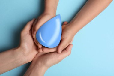 Kadın ve çocuğu açık mavi arka planda su damlacıklarını tutuyorlar. Ekoloji koruması
