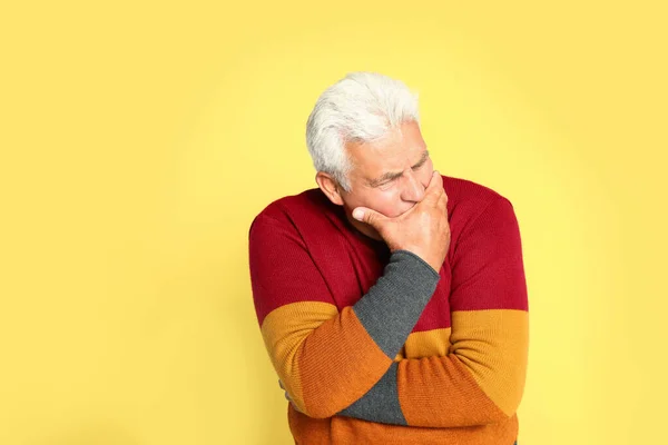 黄色の背景で咳を抑える先輩 風邪の症状 — ストック写真