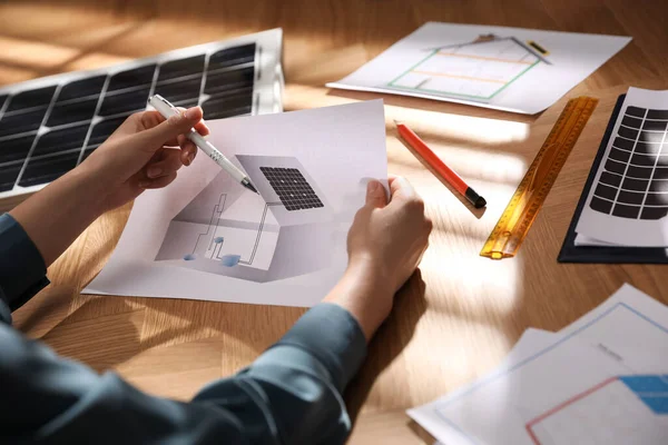 Woman working on house project with solar panels at table in office, closeup