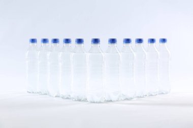 Beyaz zemin üzerinde saf su bulunan plastik şişeler.