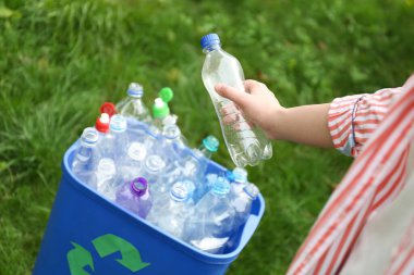 Dışarıdaki çöp kutusuna kullanılmış şişe atan kadın, yakın plan. Plastik geri dönüşümü