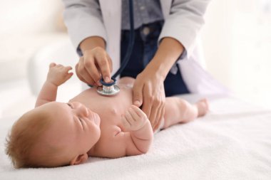 Doktor, şirin bebeği steteskopla muayene ediyor, yakın plan. Sağlık hizmetleri