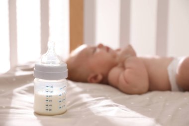 Karyolada uyuyan sağlıklı bebek, sütle şişeye odaklan.