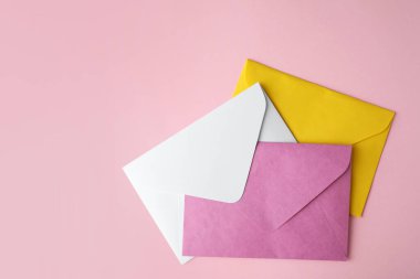 Pembe arka planda renkli kağıt zarflar, düz yatış