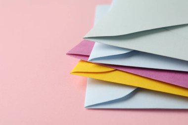 Pembe arka planda renkli zarflar yığını, yakın plan. Metin için boşluk